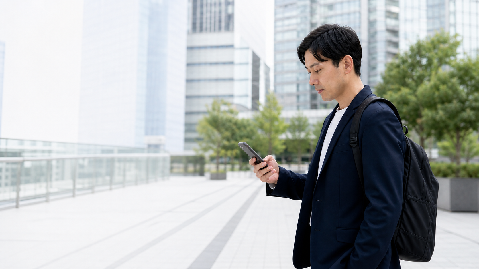 都市部の営業先へ向かう途中、スマートフォンで次の訪問を確認する営業担当者